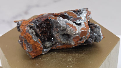 Mineral specimen on a wooden stand with a marble background
