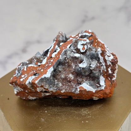 Mineral sample on a wooden stand with a marble background