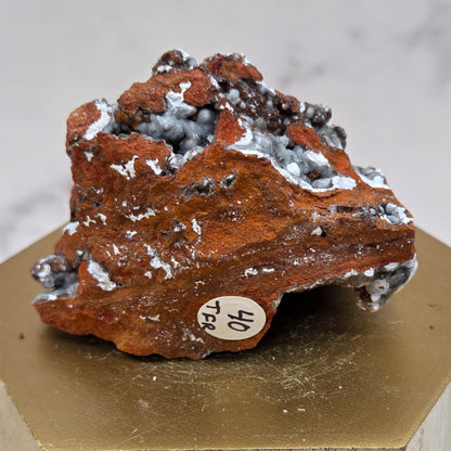 Mineral sample with a label on a wooden stand against a neutral background