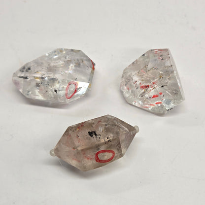 Three clear quartz crystals on a light gray background