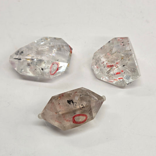 Three clear quartz crystals on a light gray background