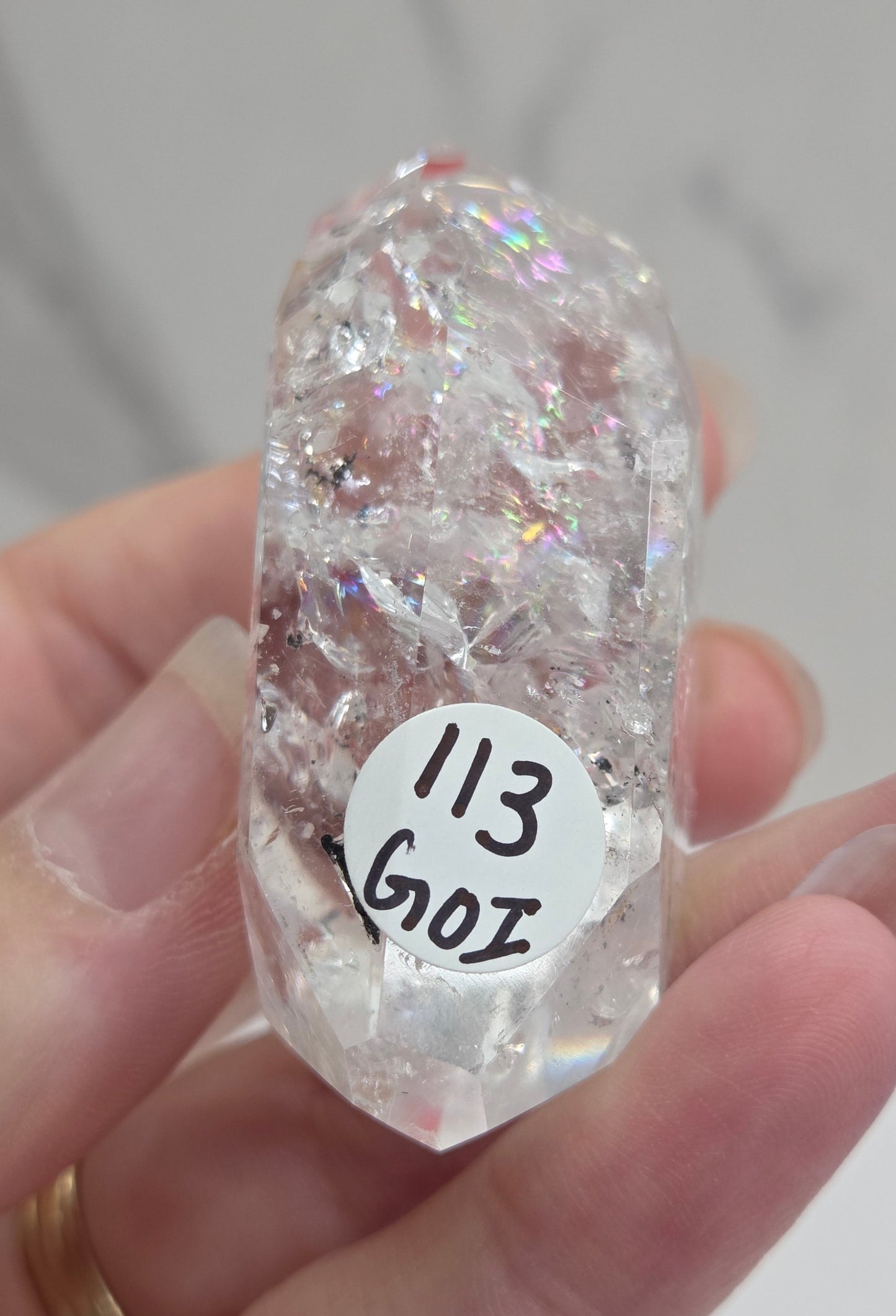 Clear Quartz held between fingers against a neutral background