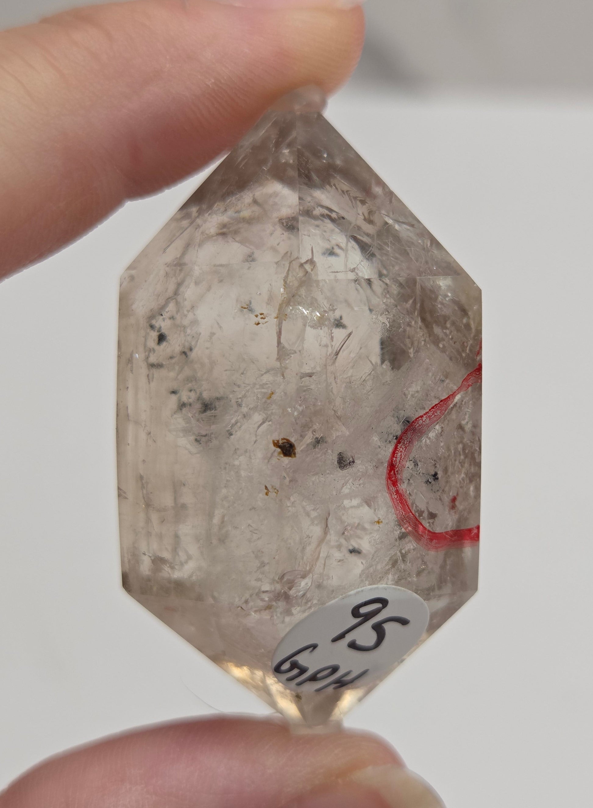Clear Quartz held between fingers against a neutral background