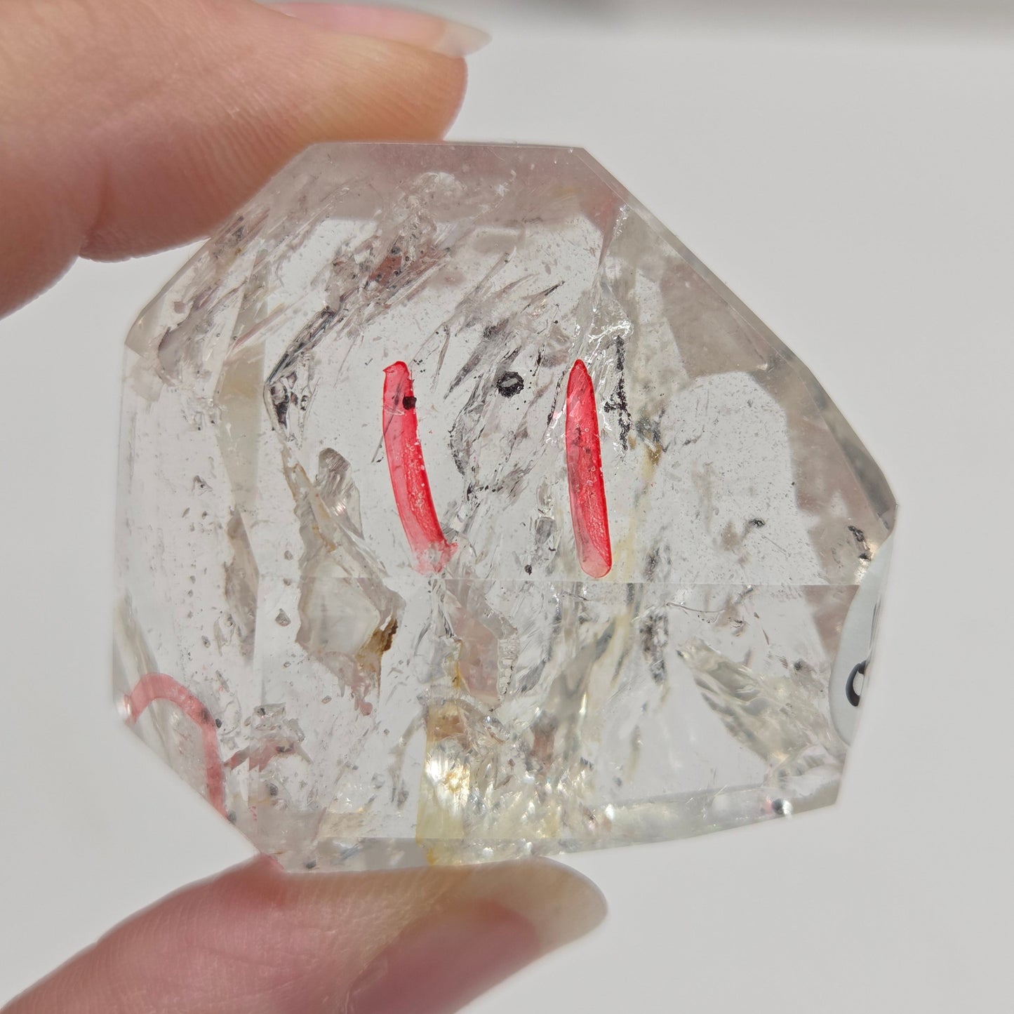 Clear crystal held by a hand against a neutral background