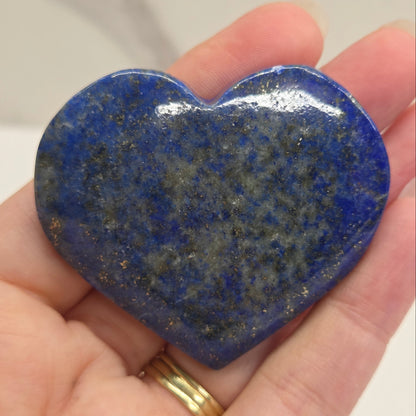 Heart-shaped blue stone held in a hand against a neutral background