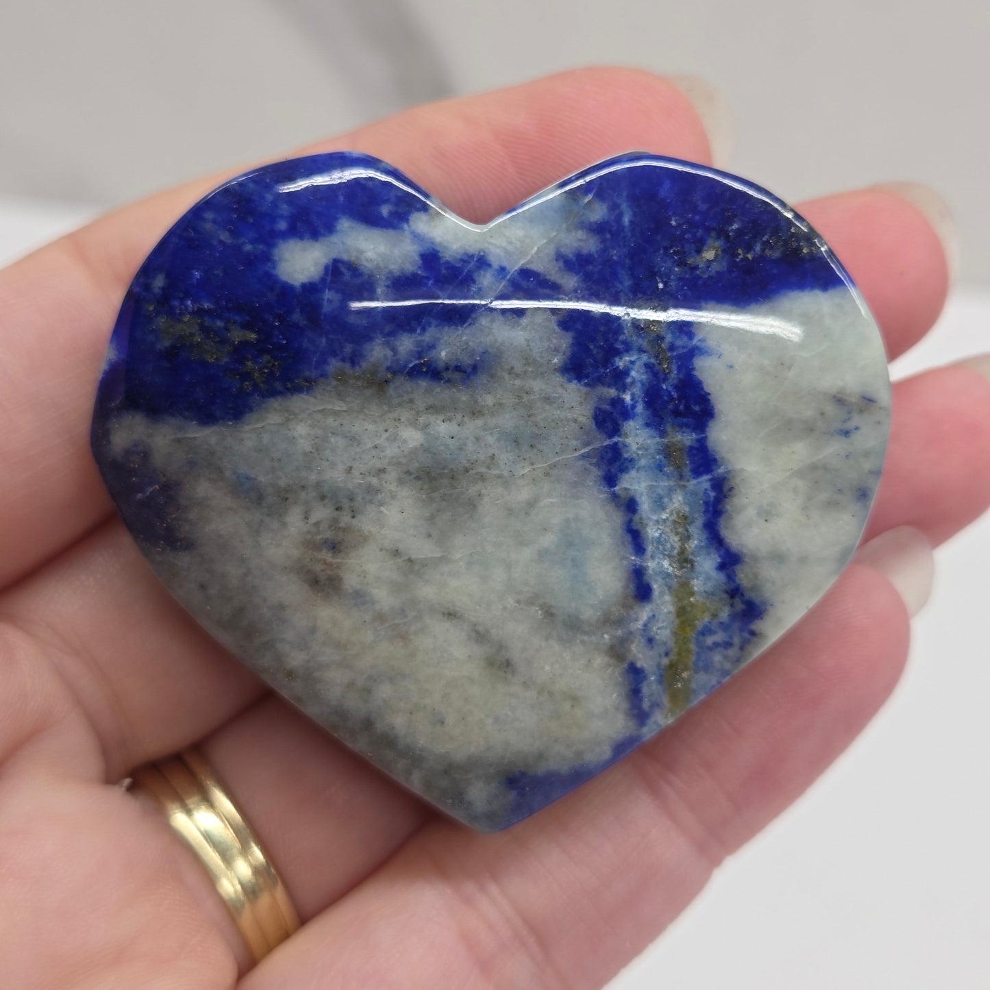 Hand holding a blue and gray stone with a blurred background
