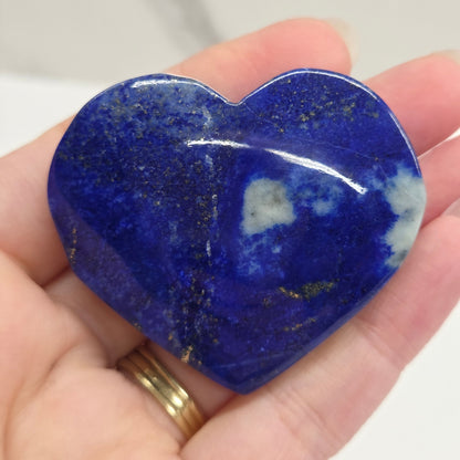 Heart-shaped blue stone held in a hand against a neutral background