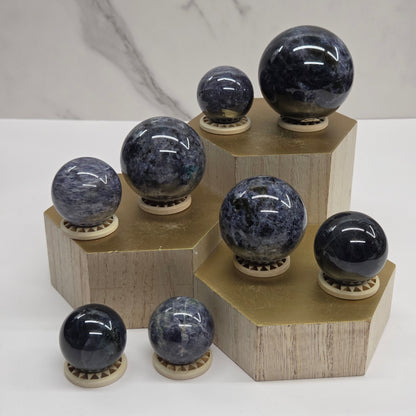 Dark blue and black spheres on a wooden stand against a neutral background