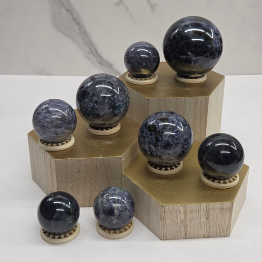 Dark blue and black spheres on a wooden stand against a neutral background