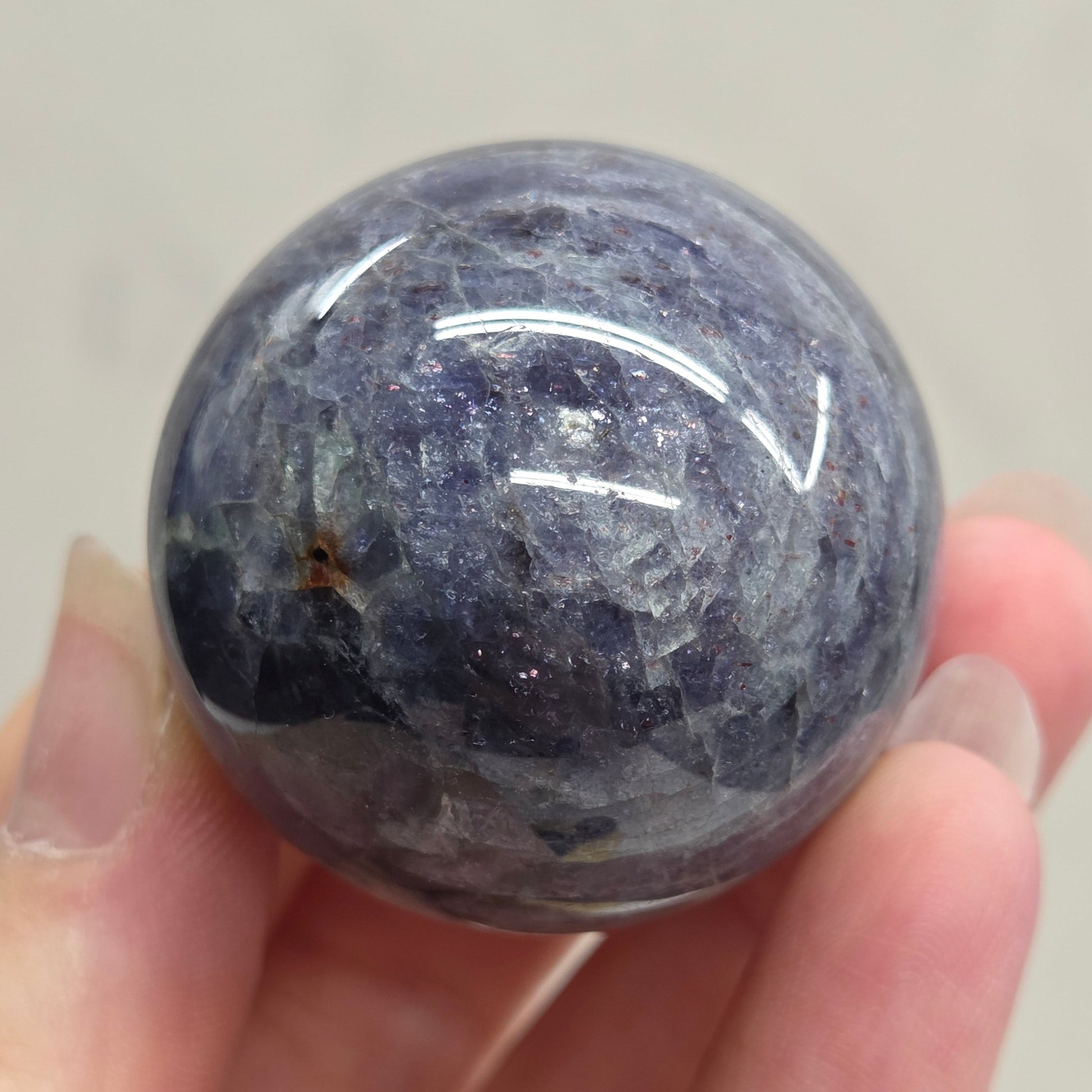 Hand holding a blue stone sphere against a neutral background