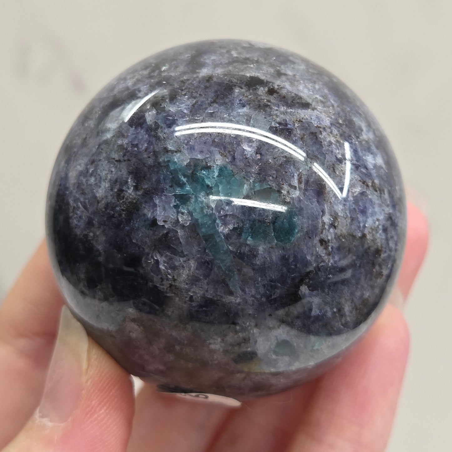 Hand holding a polished stone sphere against a neutral background