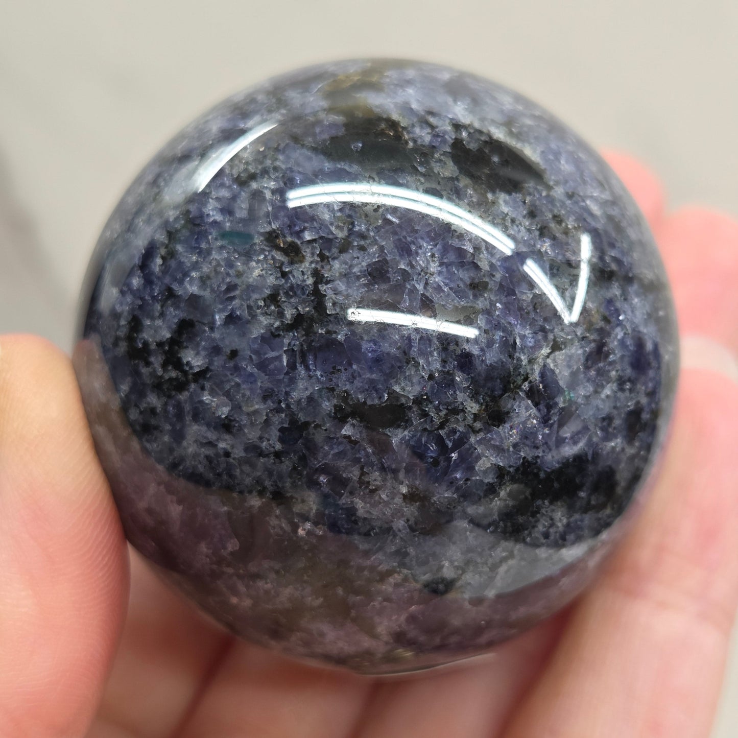 Hand holding a purple crystal ball with a plain background