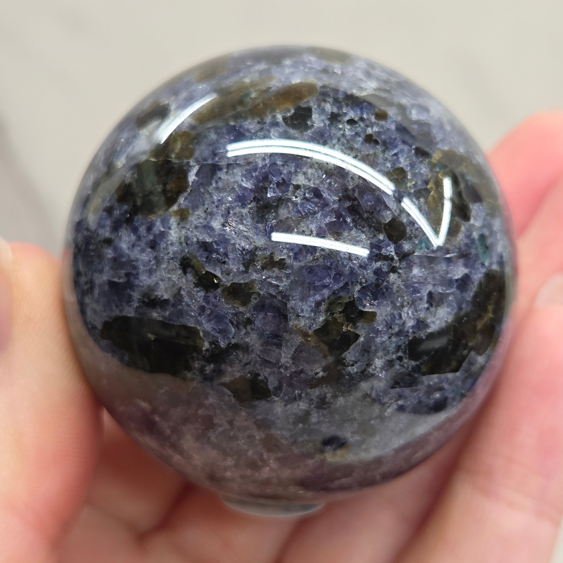 Hand holding a translucent purple crystal ball with a white background