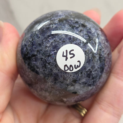 Round stone with a white label held in a hand against a neutral background