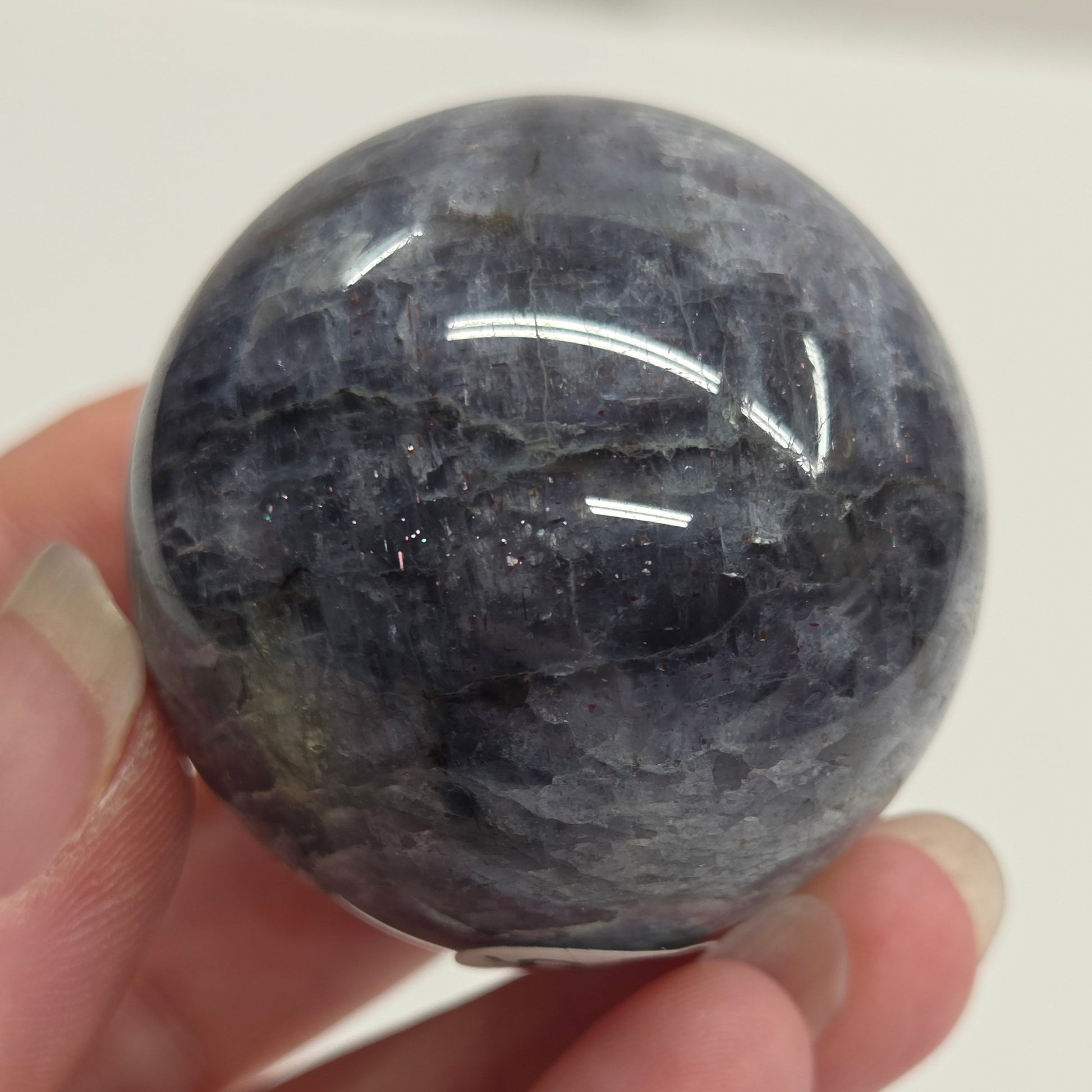 Hand holding a dark gray stone against a white background