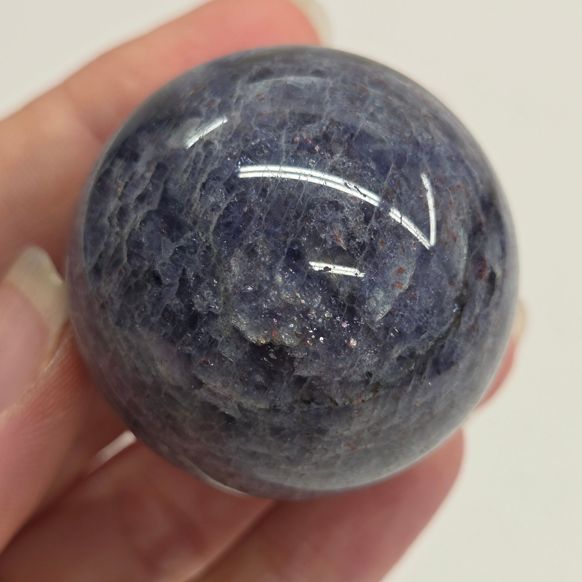 Blue stone sphere held in a hand against a white background