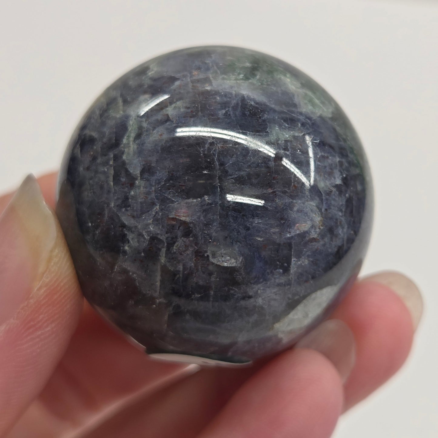 Hand holding a dark blue crystal ball against a white background