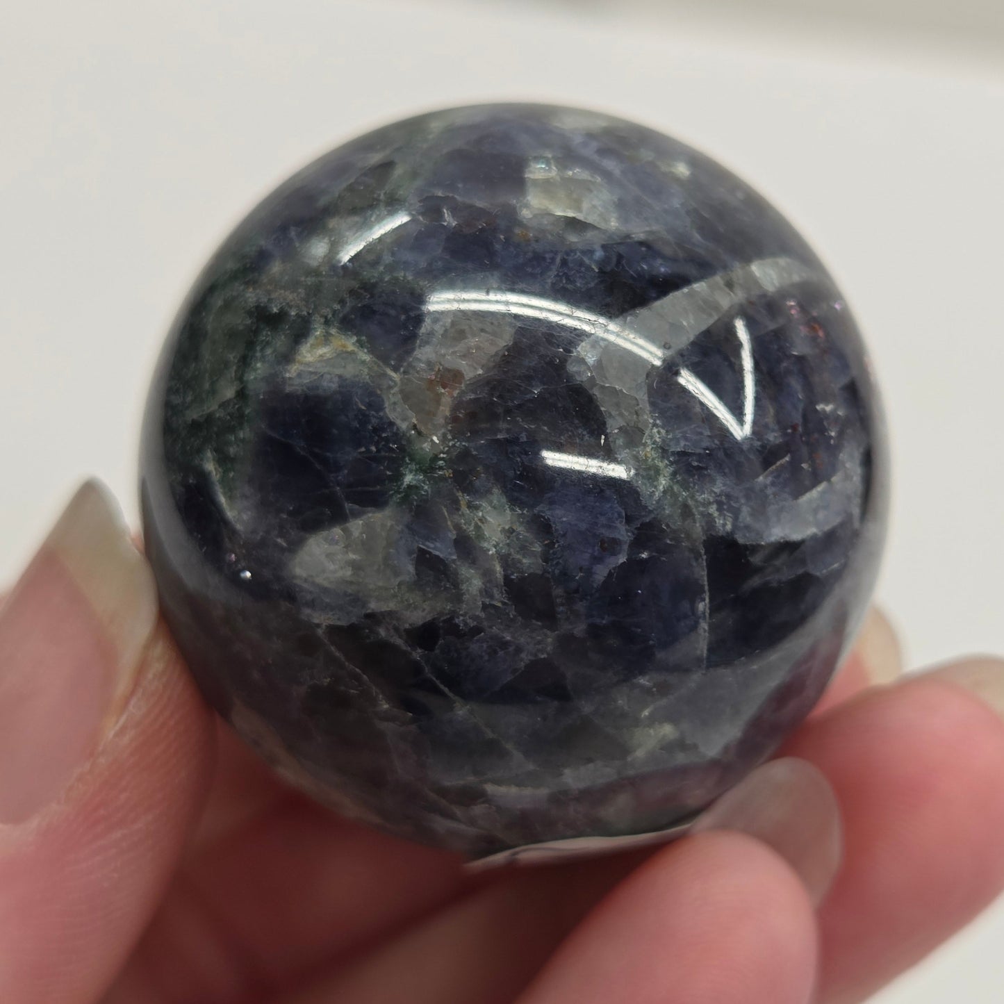 Hand holding a polished blue stone against a white background
