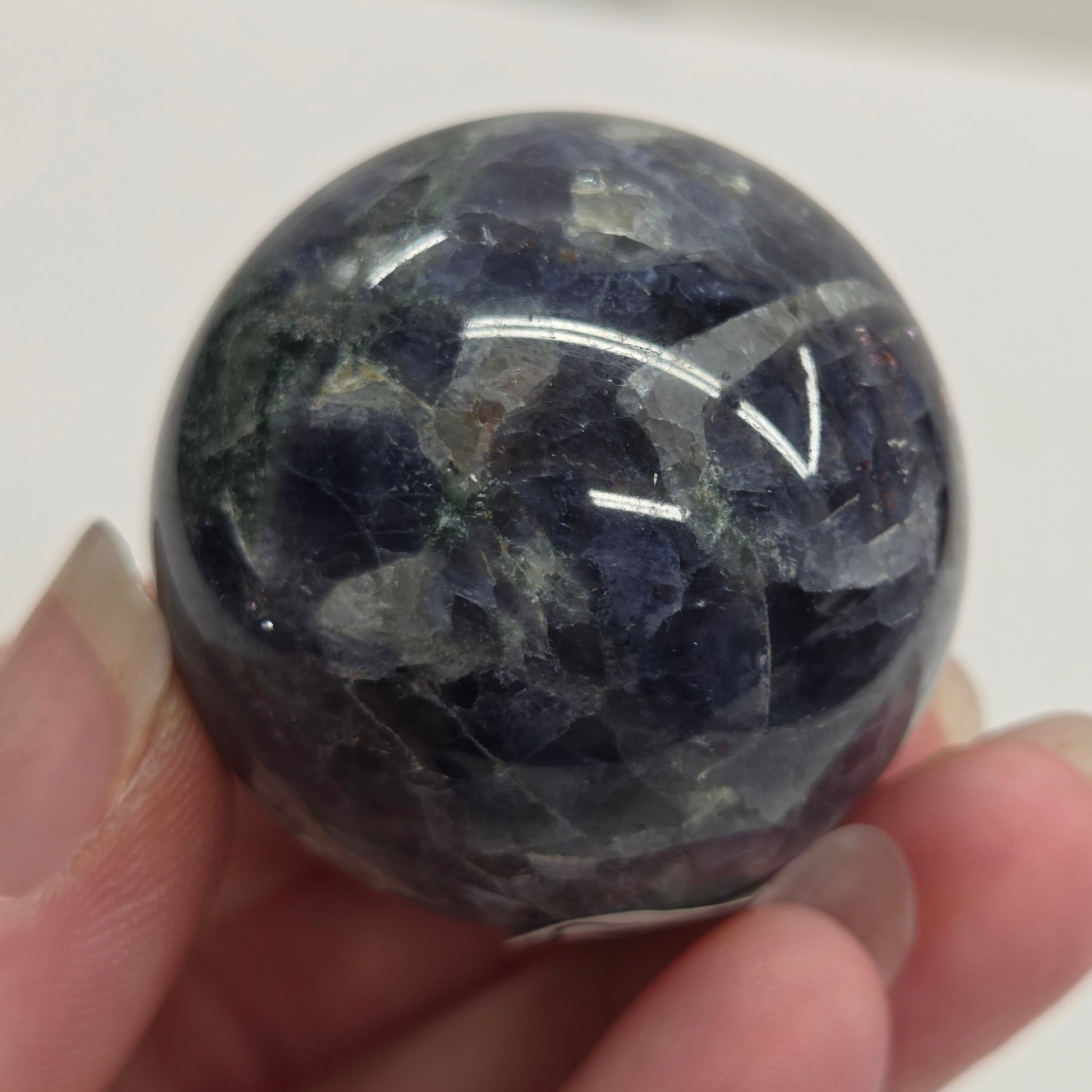 Hand holding a polished blue stone against a white background