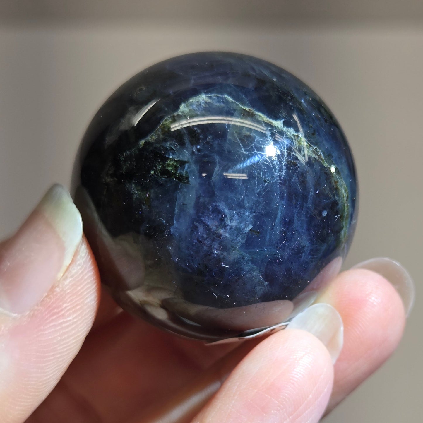 Hand holding a dark blue stone against a blurred background