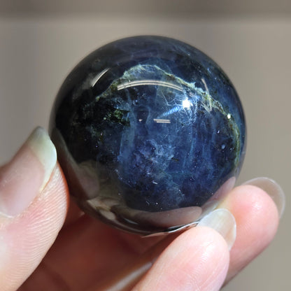 Hand holding a dark blue stone against a blurred background