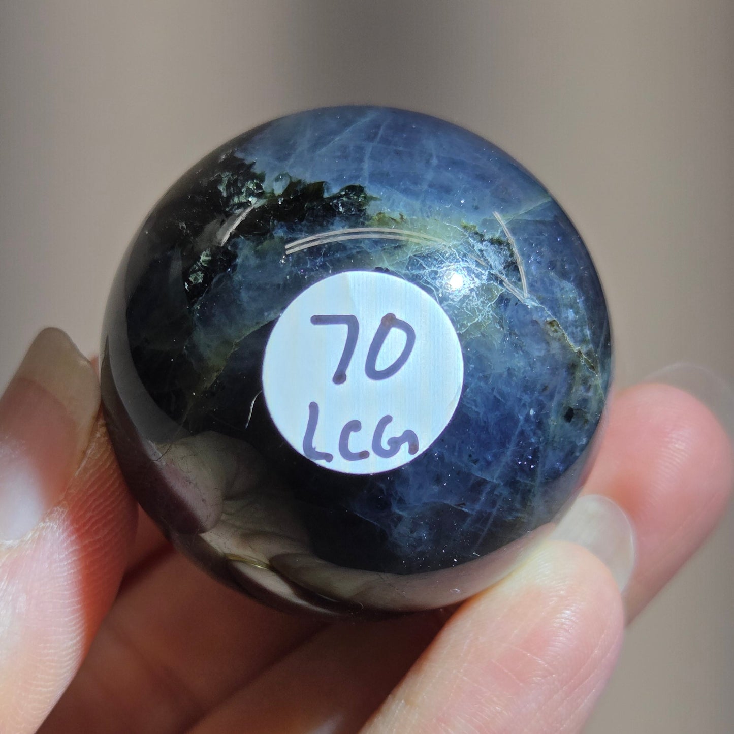 Hand holding a blue and black crystal with a label on a blurred background