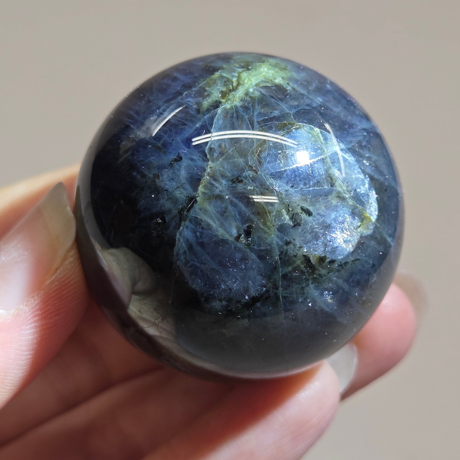 Hand holding a polished blue stone against a neutral background