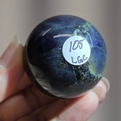 Hand holding a dark blue marbled object with a label on a neutral background