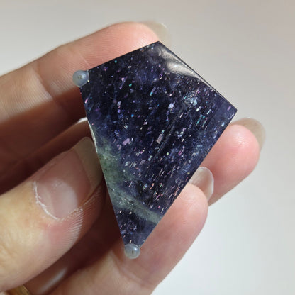 Hand holding a dark purple crystal against a plain background