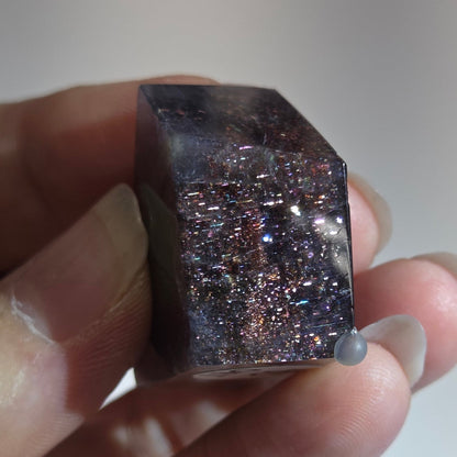 Hand holding a small purple crystal against a blurred background