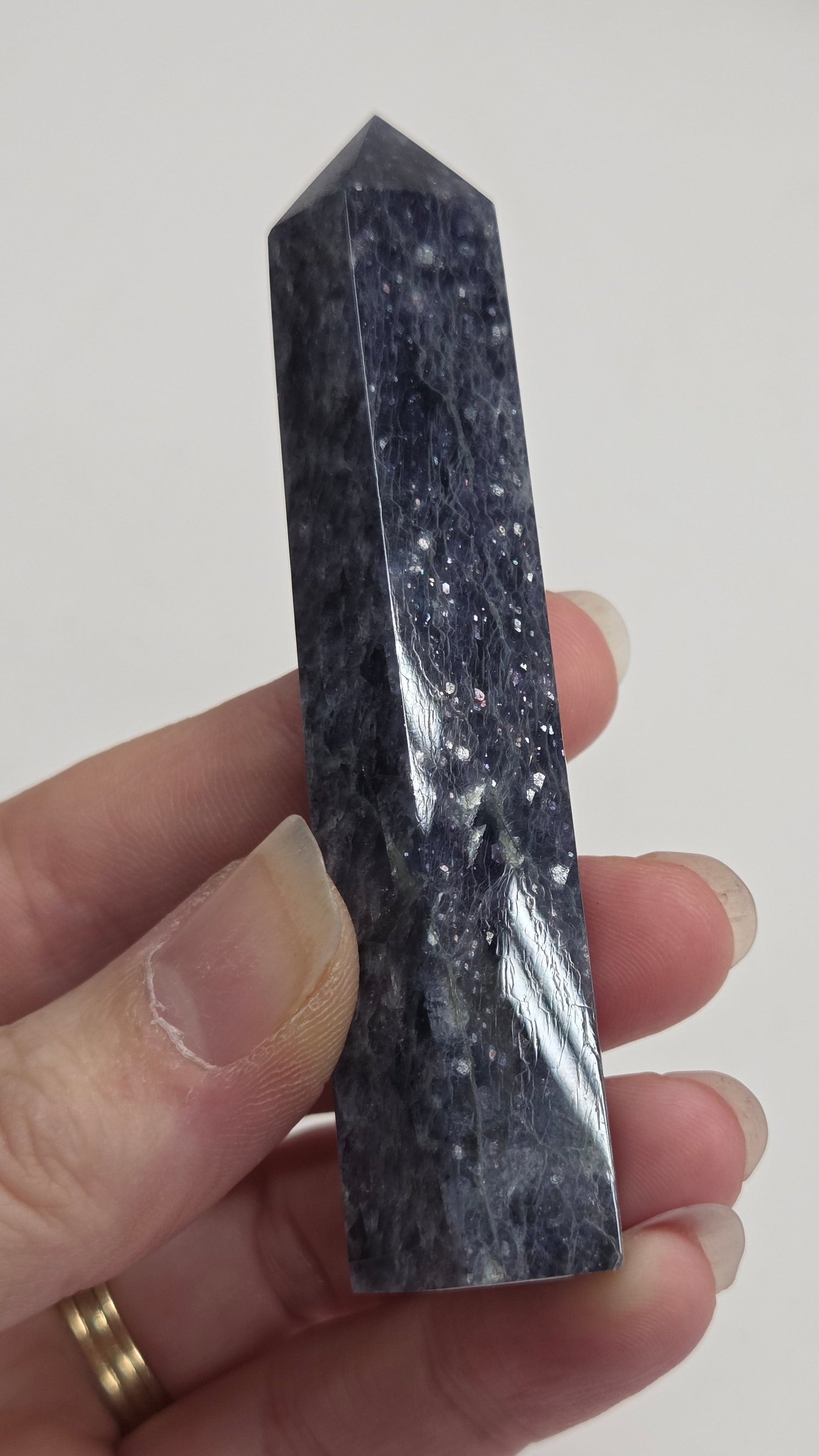 Hand holding a dark crystal prism against a plain background
