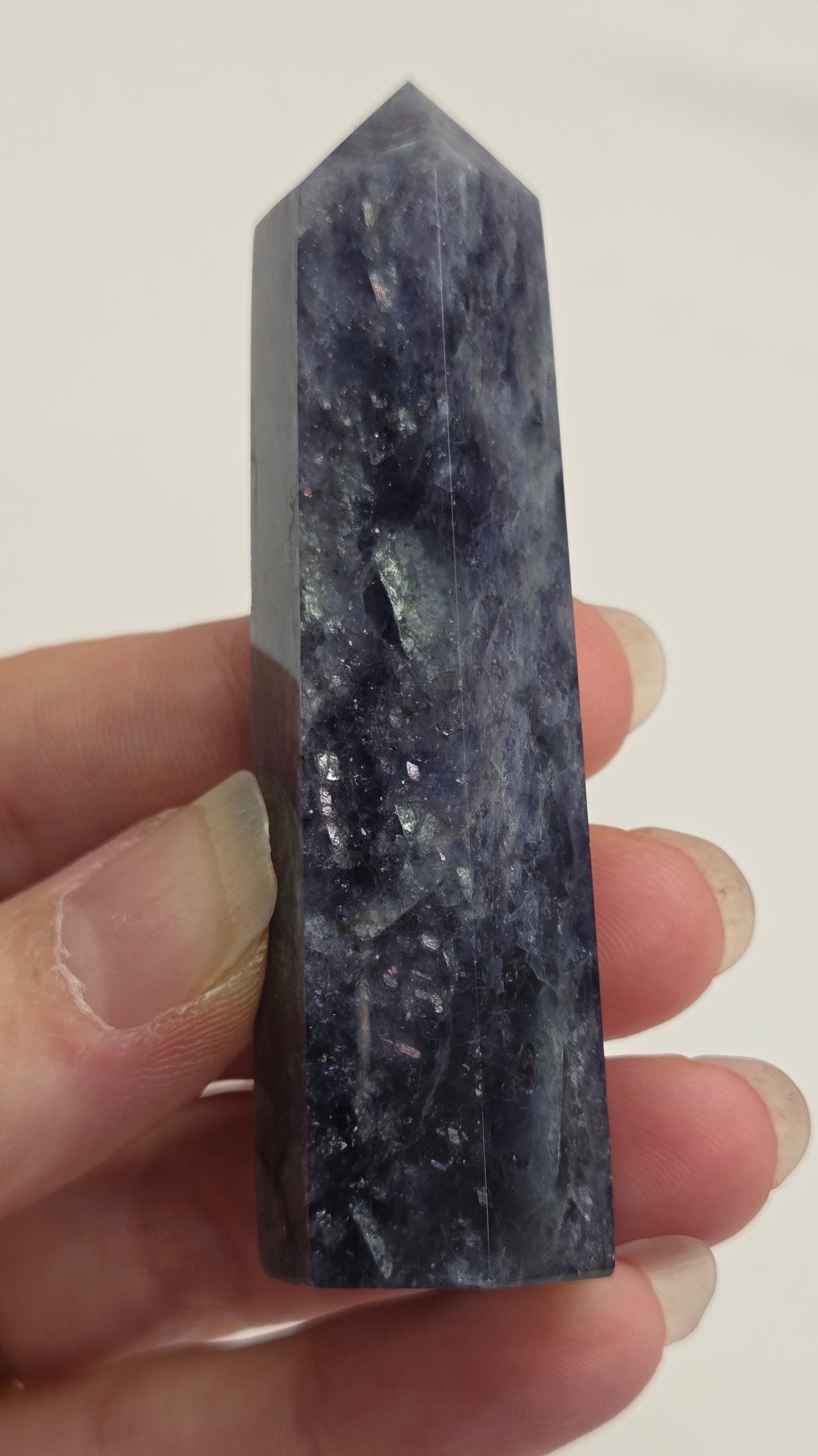 Hand holding a dark crystal against a plain background