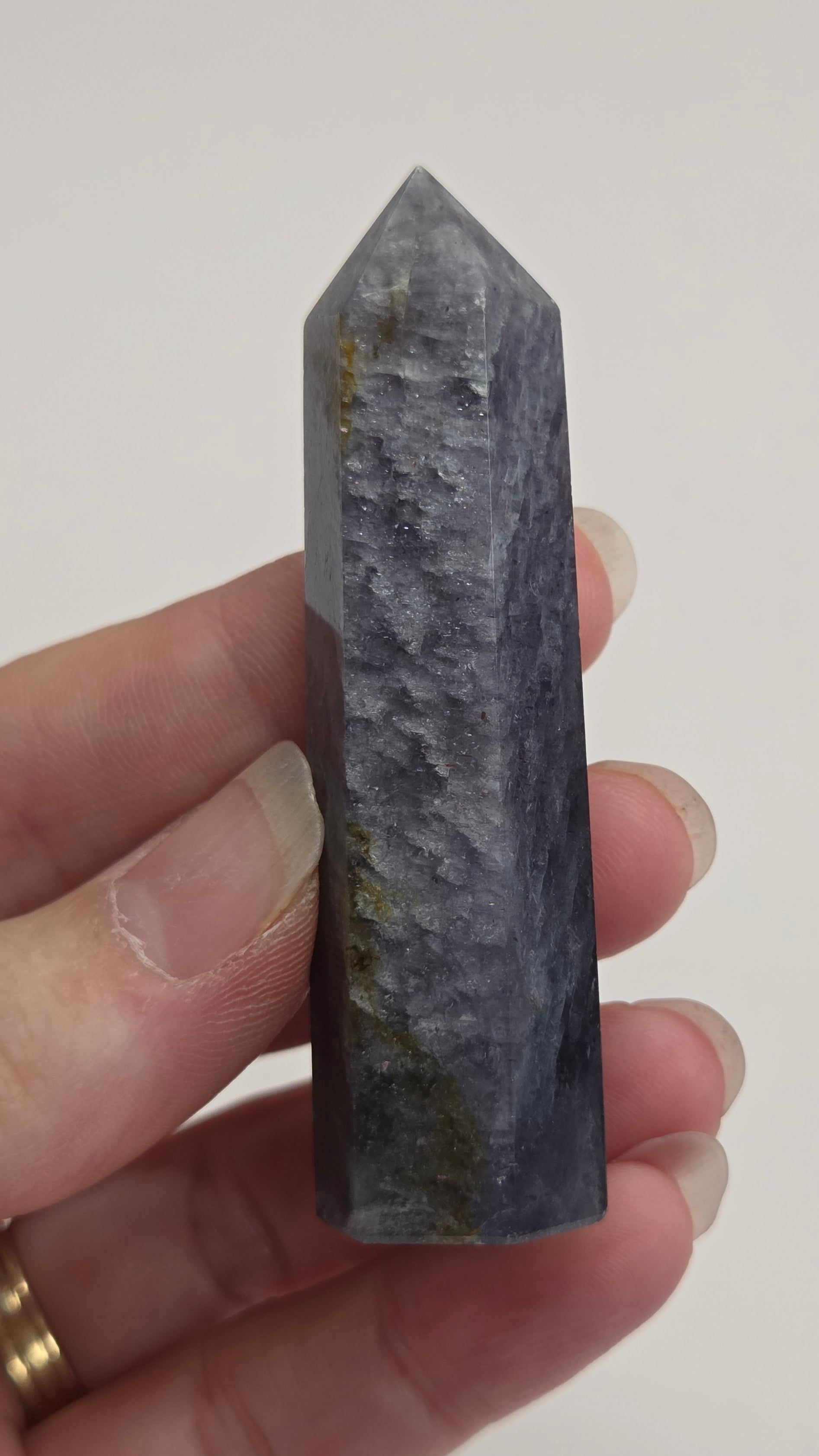 Hand holding a dark blue crystal against a plain background