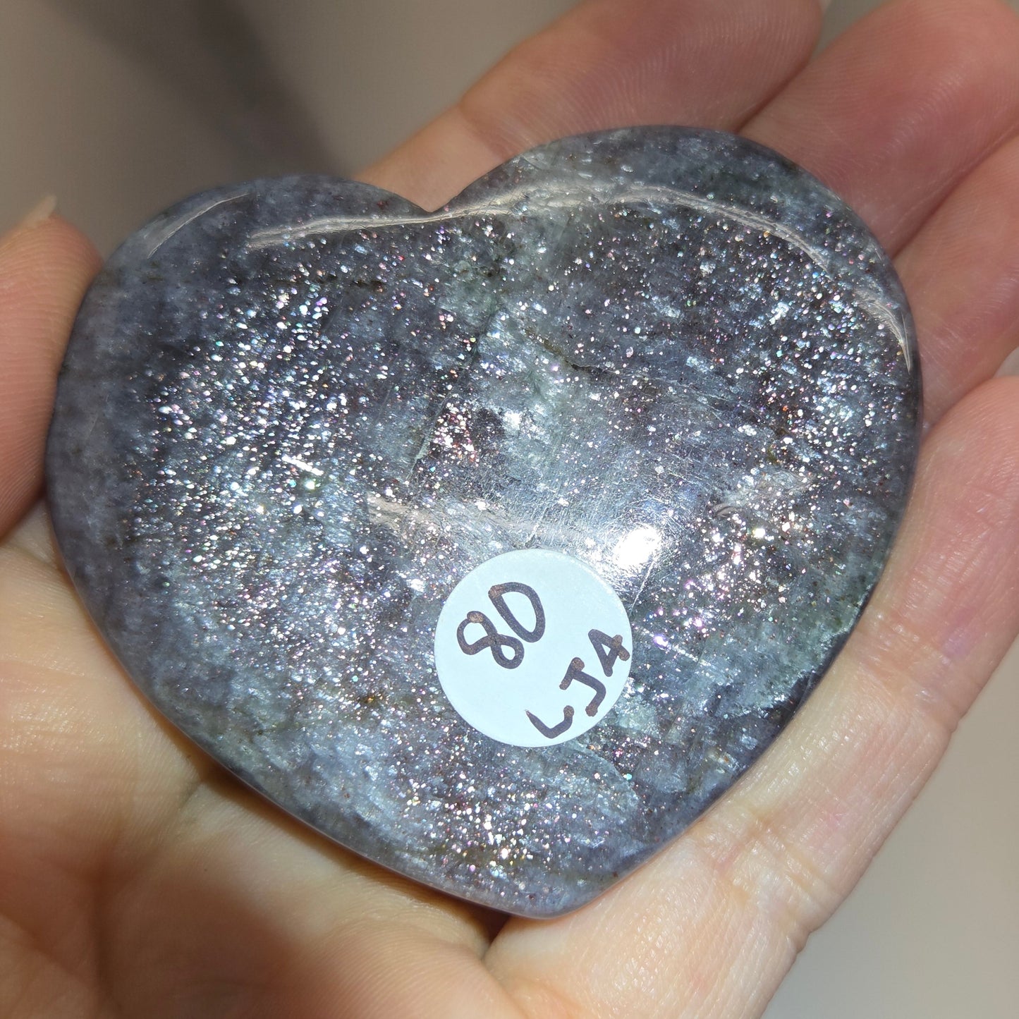 Hand holding a large purple heart shaped crystal 