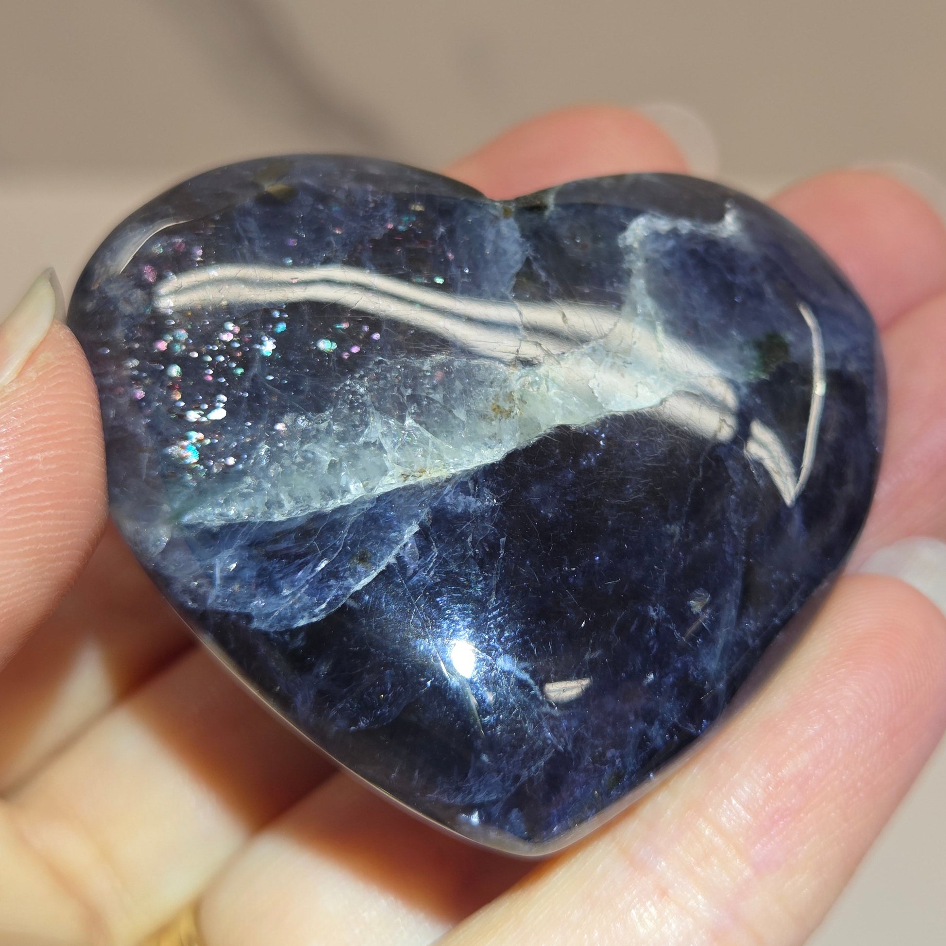 Hand holding a large purple heart shaped crystal 