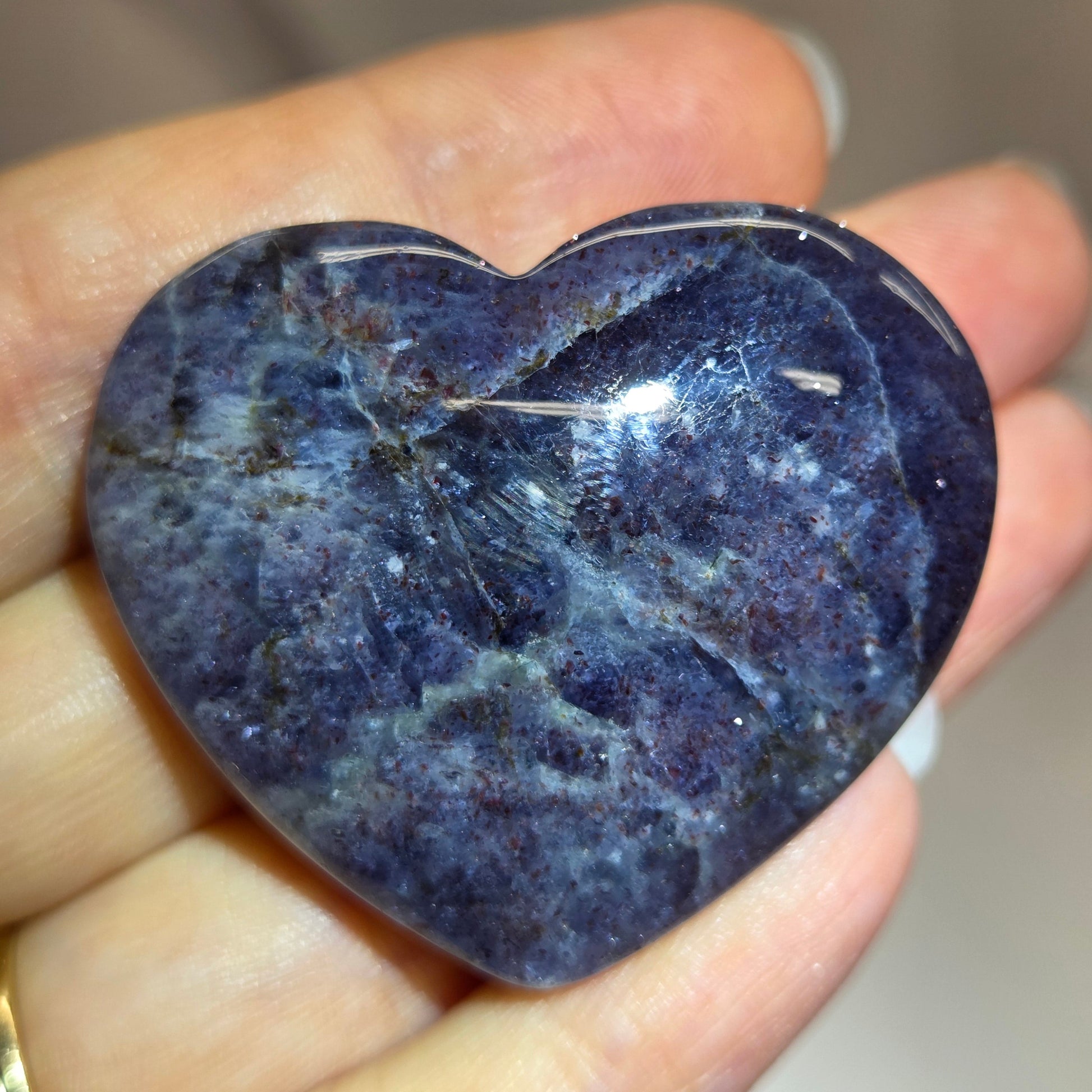 Hand holding a large purple heart shaped crystal 