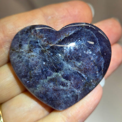 Hand holding a large purple heart shaped crystal 