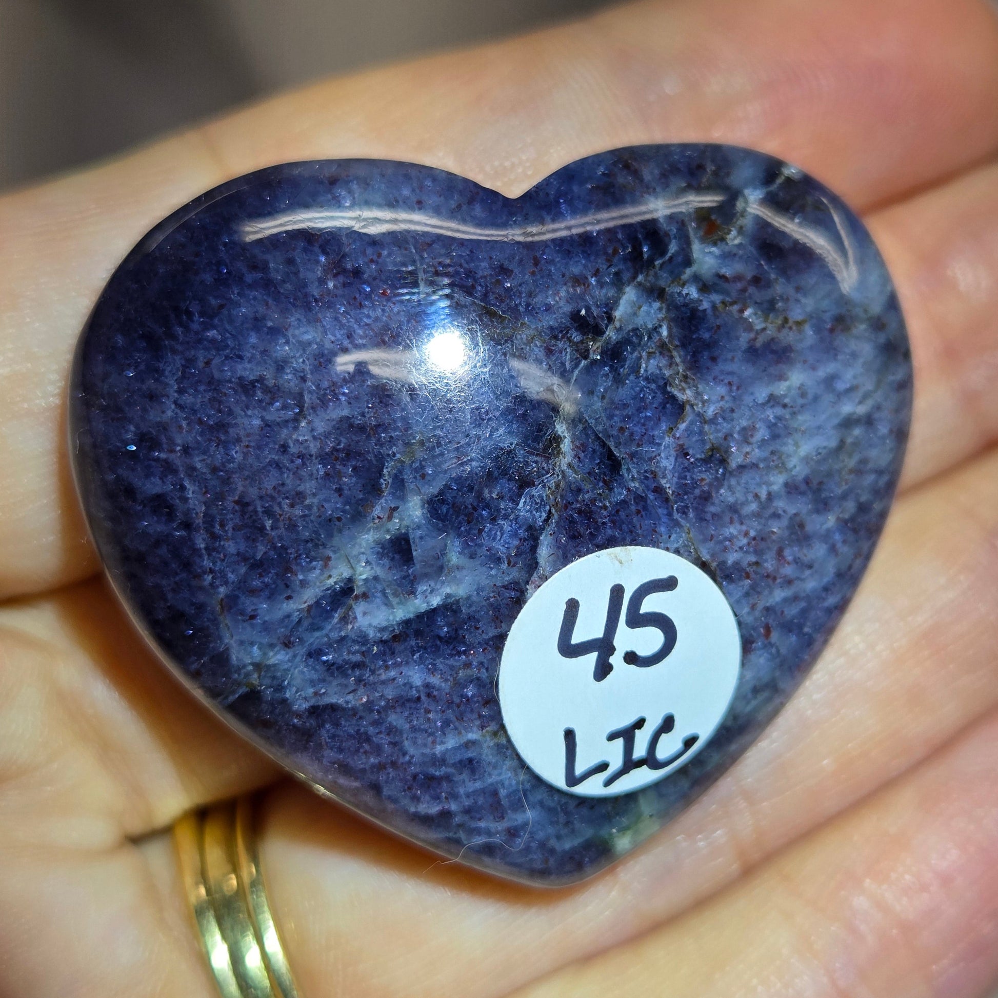Hand holding a large purple heart shaped crystal 