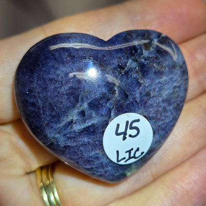 Hand holding a large purple heart shaped crystal 