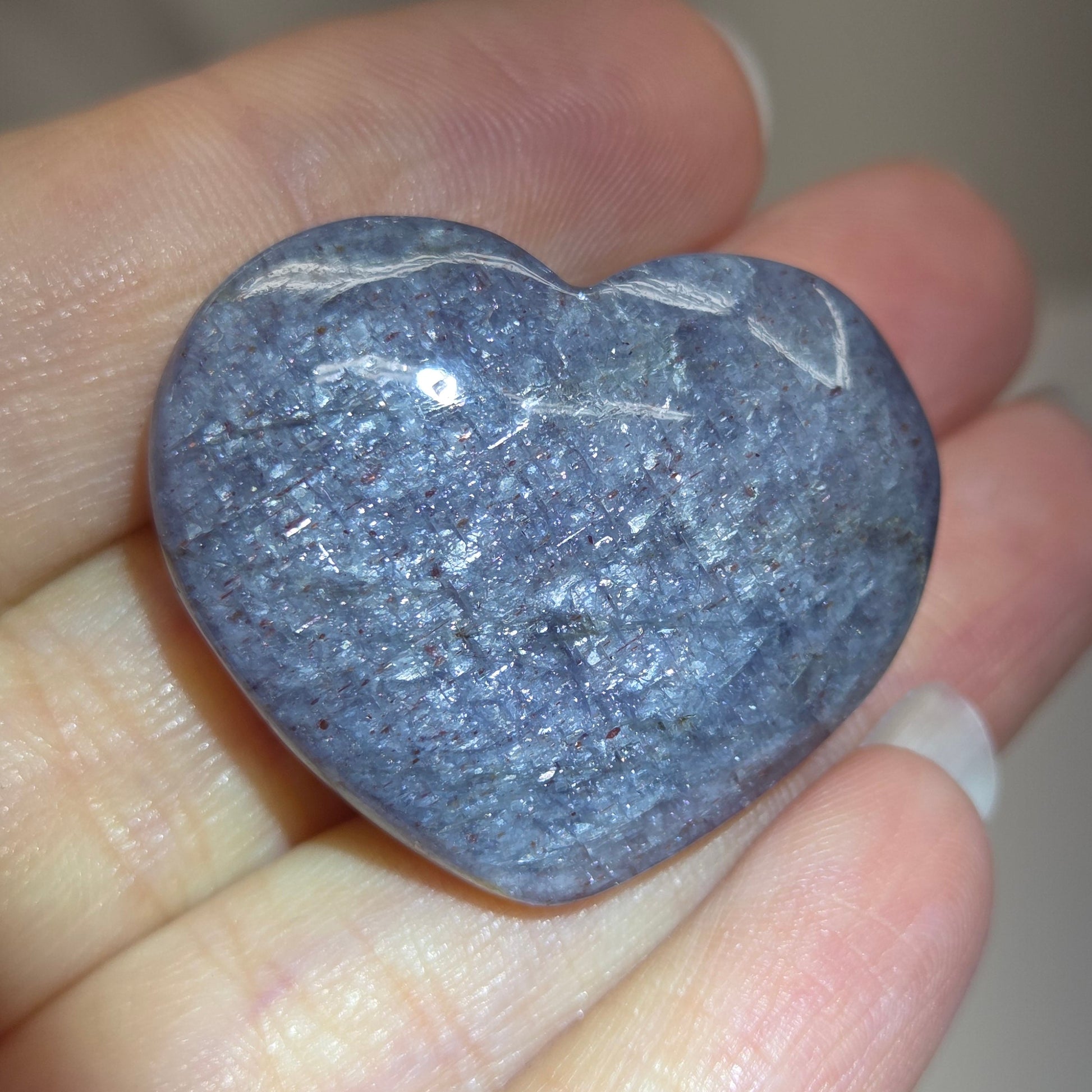 Hand holding a large purple heart shaped crystal 