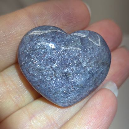 Hand holding a large purple heart shaped crystal 