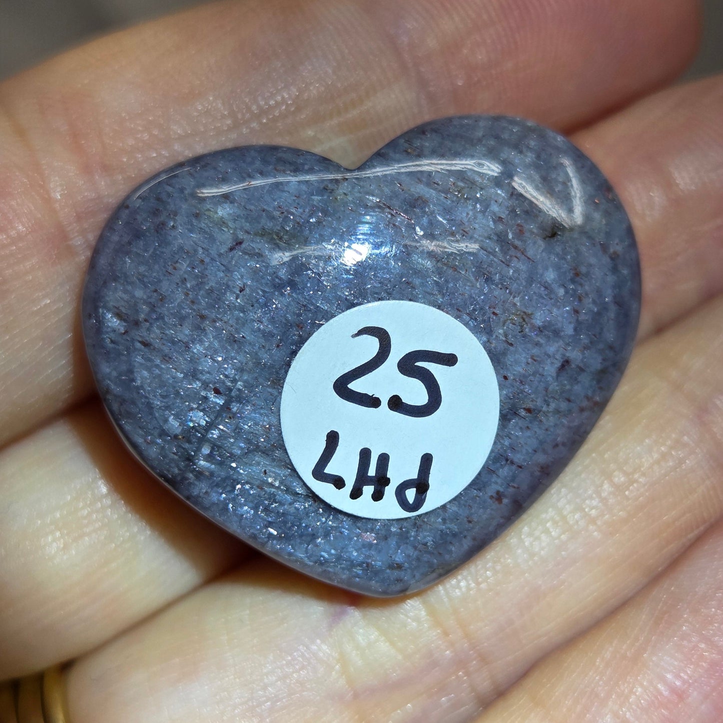Hand holding a large purple heart shaped crystal 