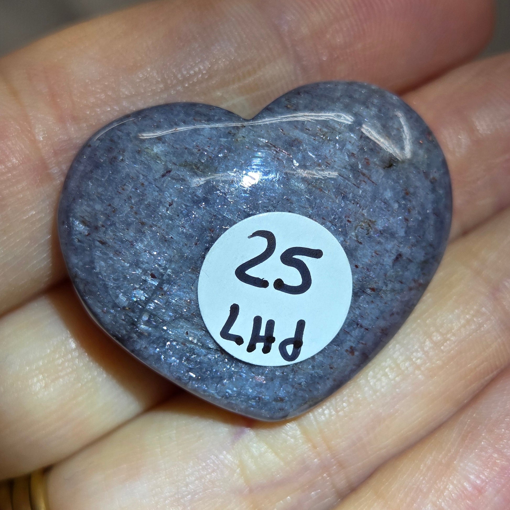 Hand holding a large purple heart shaped crystal 