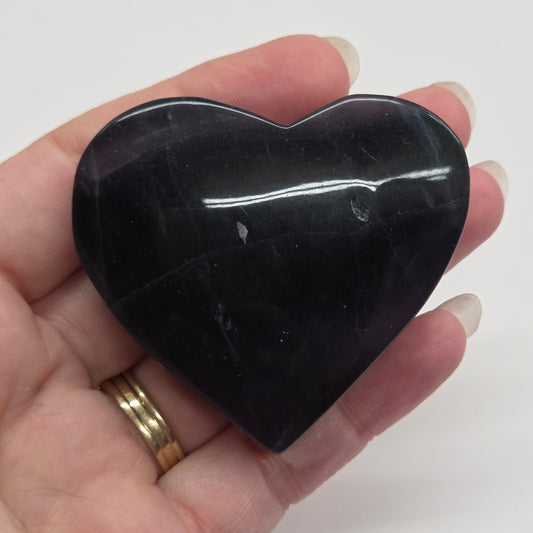 Hand holding a black stone against a white background