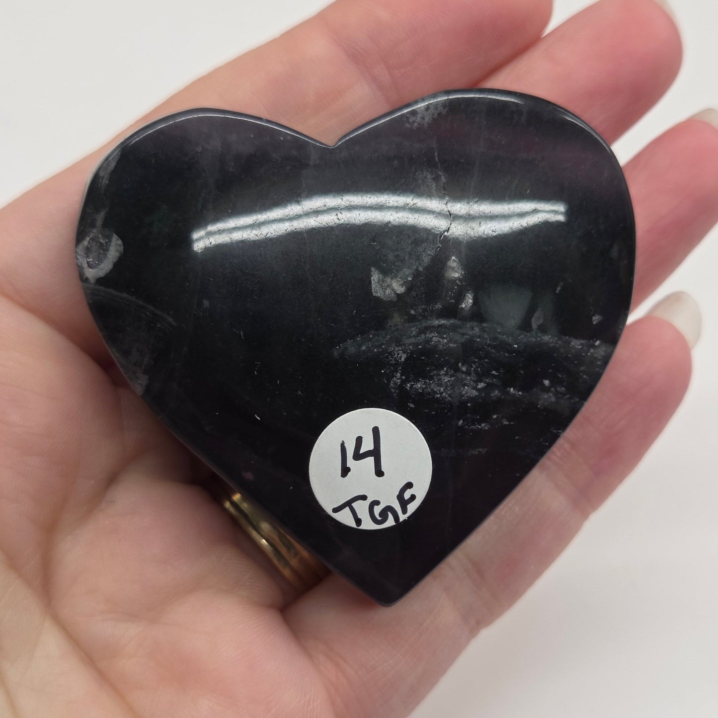 Heart-shaped black stone held in a hand with a white background