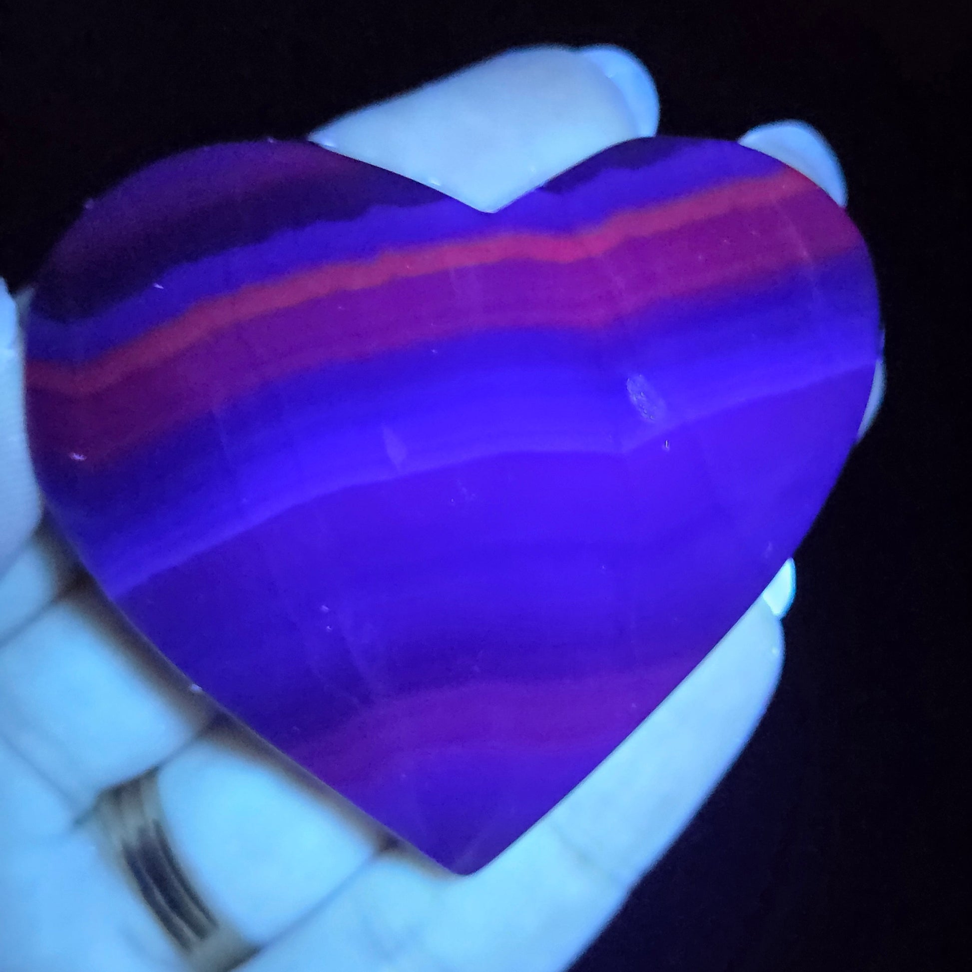 Purple stone held in a hand against a dark background
