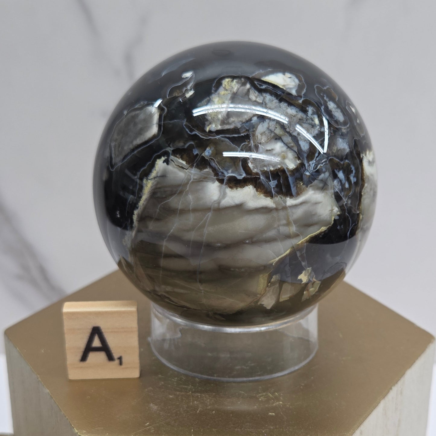 Brown and black crystal spheres on acrylic holders and a wooden stand against a neutral background