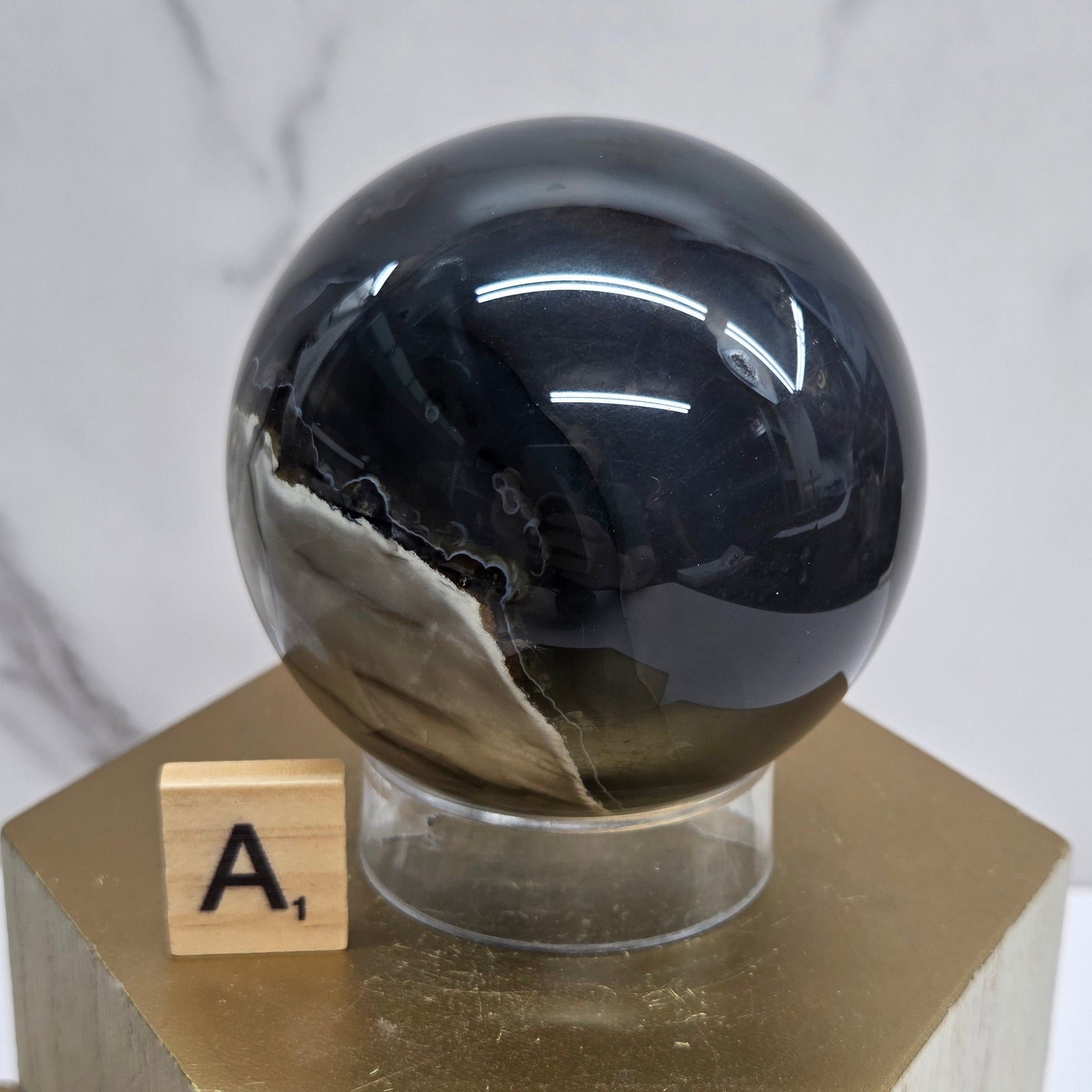 Brown and black crystal spheres on acrylic holders and a wooden stand against a neutral background