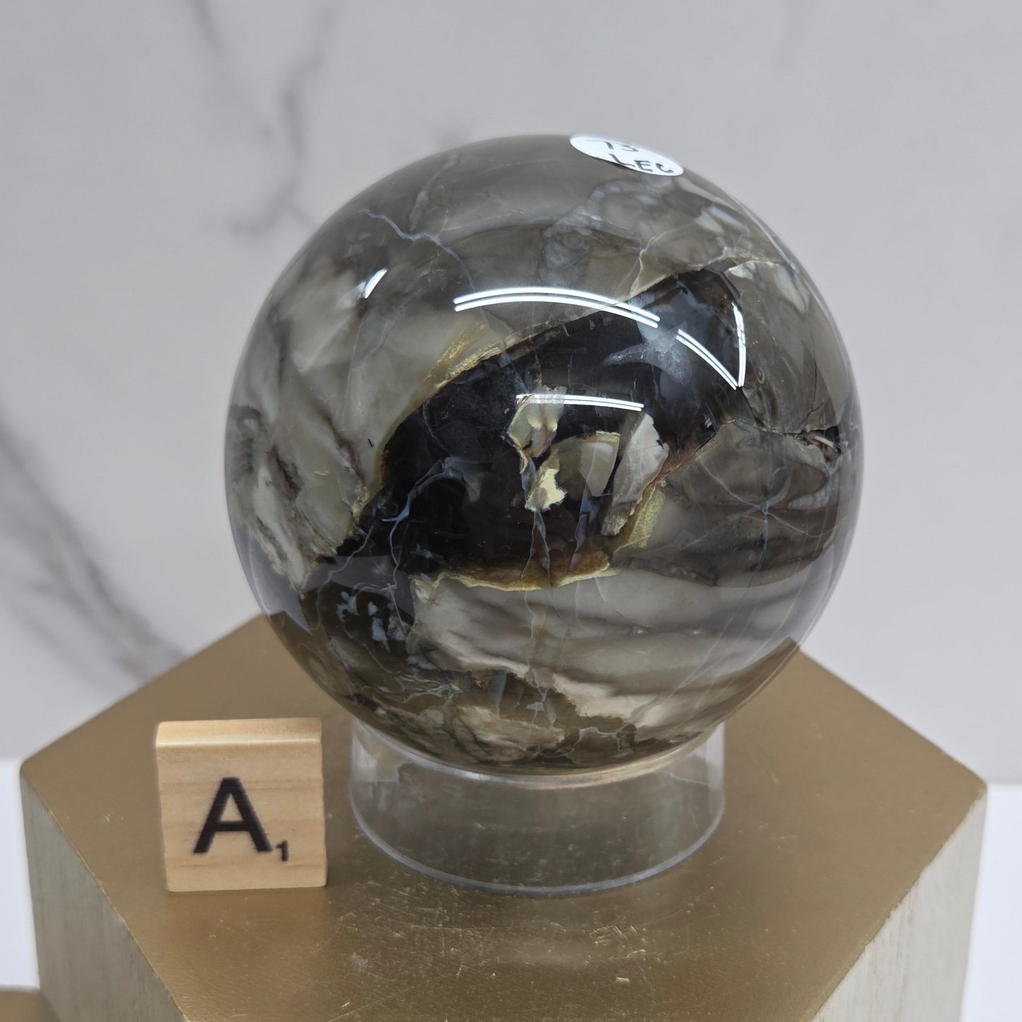 Brown and black crystal spheres on acrylic holders and a wooden stand against a neutral background