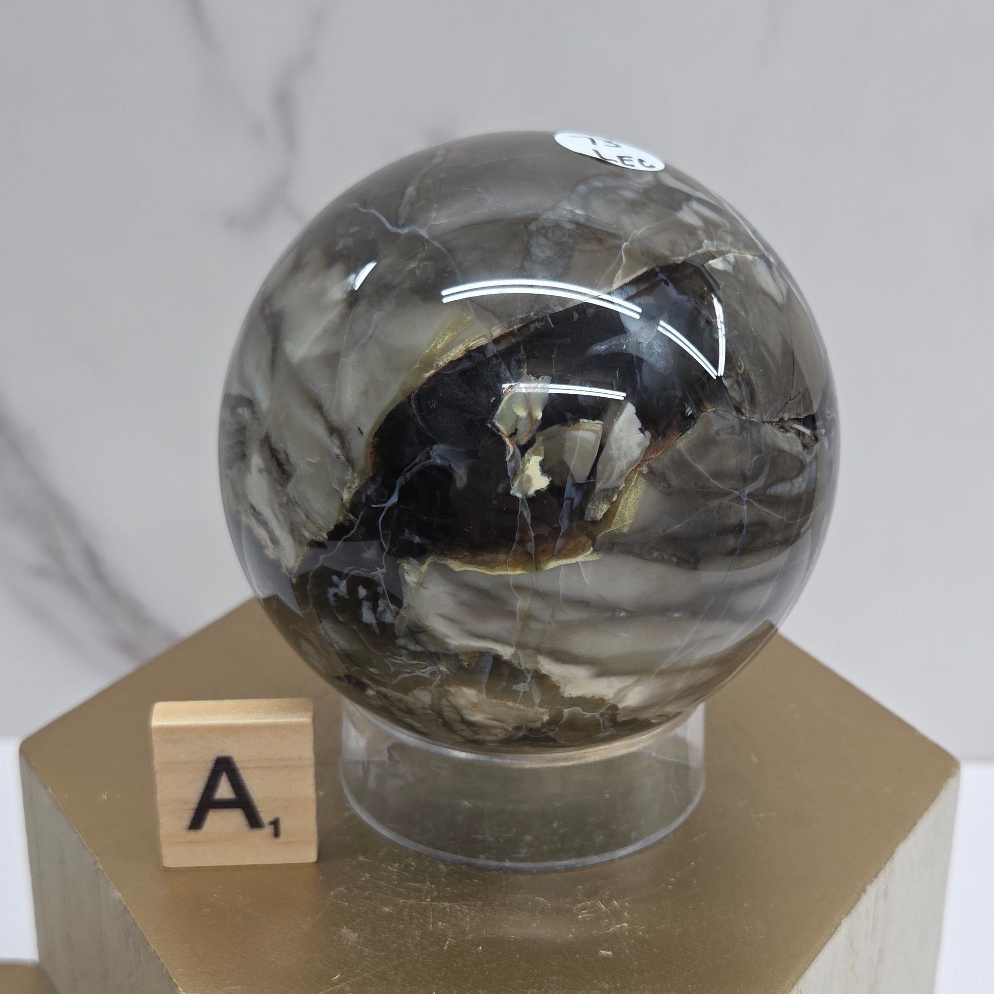 Brown and black crystal spheres on acrylic holders and a wooden stand against a neutral background